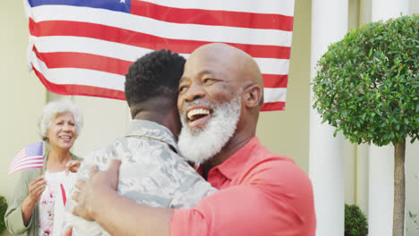 soldado afroamericano abrazando a su padre sonriente sobre la familia y la bandera estadounidense