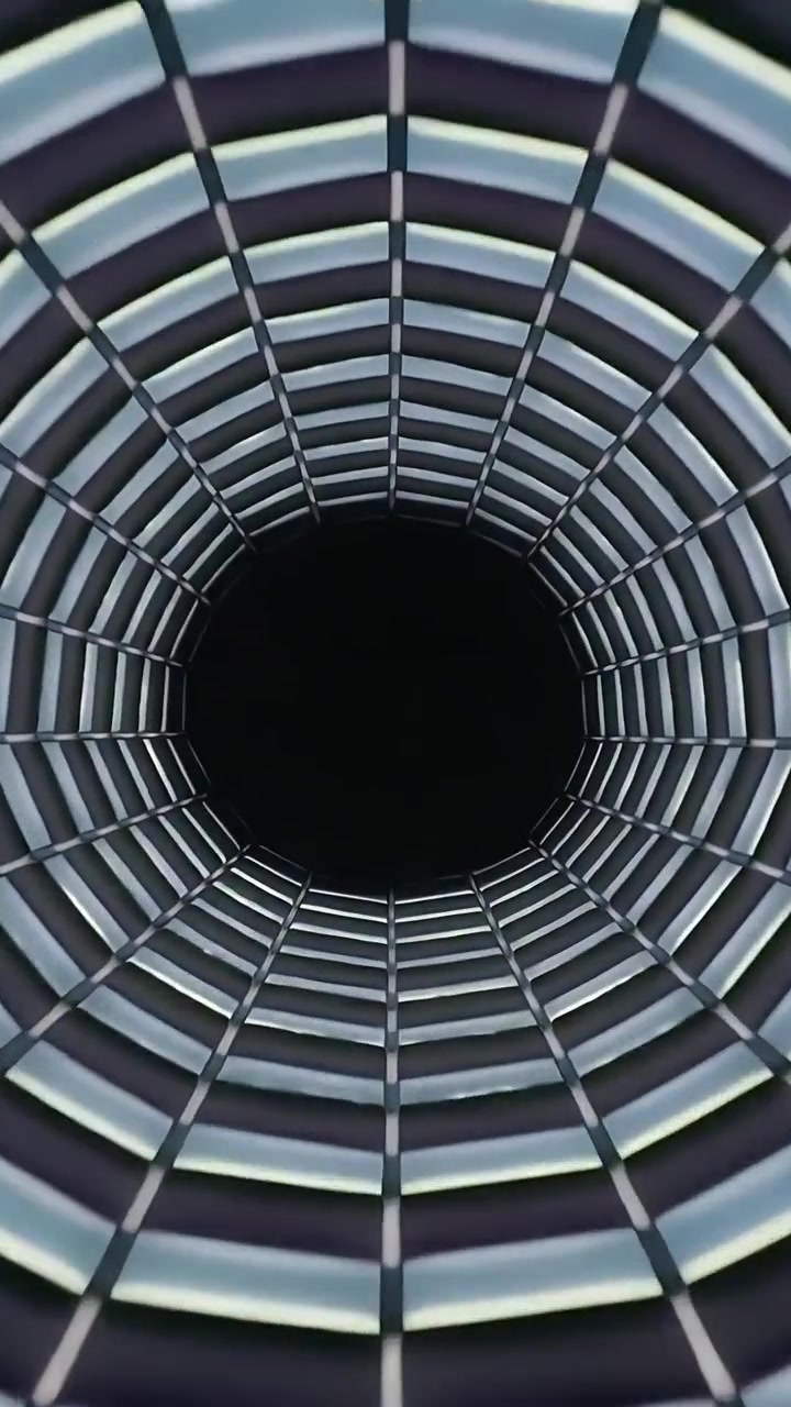 Vídeo vertical: Lente que avança, revelando túnel de grade circular para focar em vazio preto, com LED.