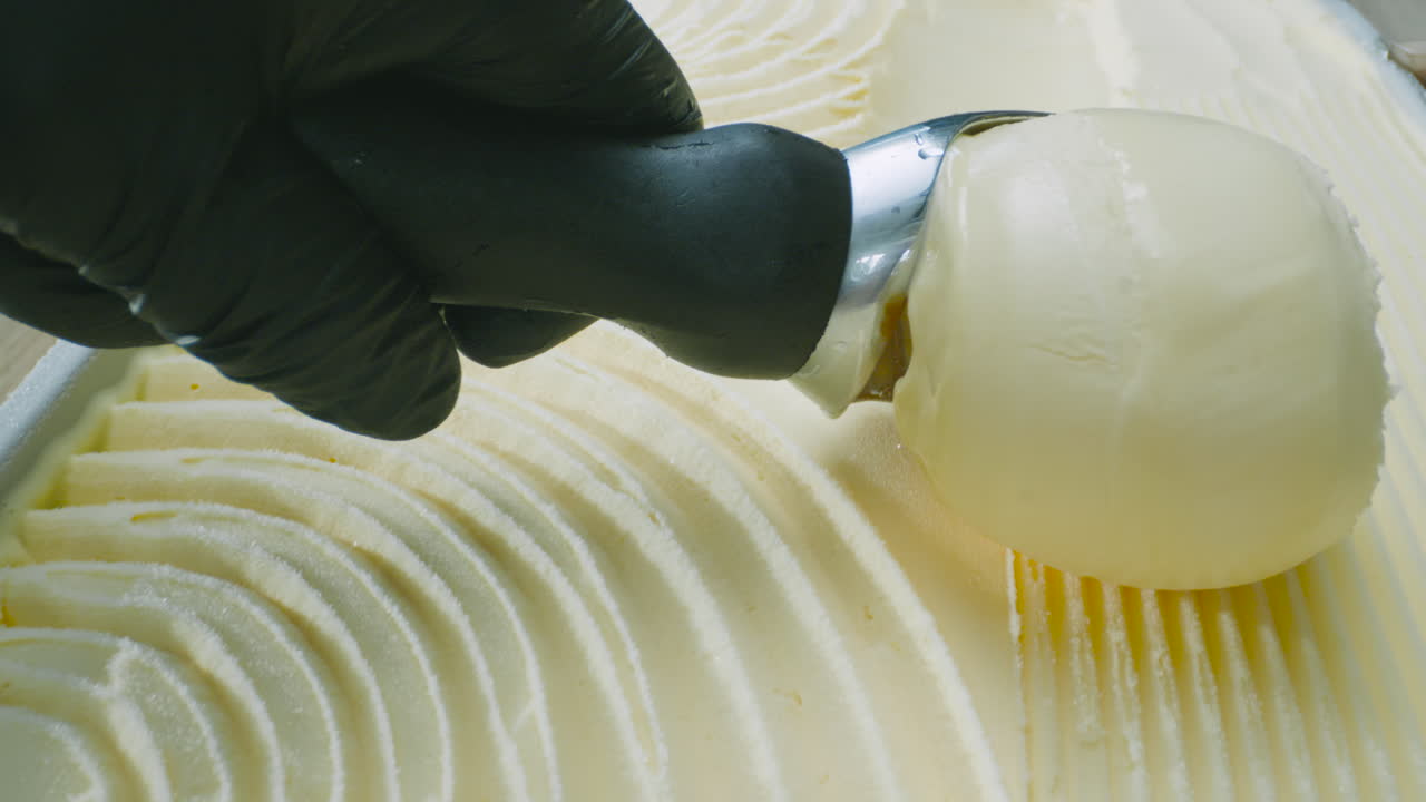 A close-up of creamy ice cream being served with a metal scoop. Smooth motion and a tempting texture captured in high definition.