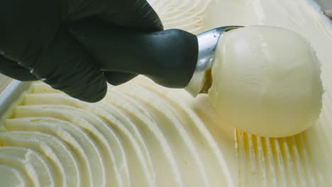 a close-up of creamy ice cream being served with a metal scoop. smooth motion and a tempting texture captured in high definition.