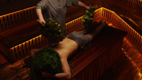 man receiving herbal treatment in a sauna