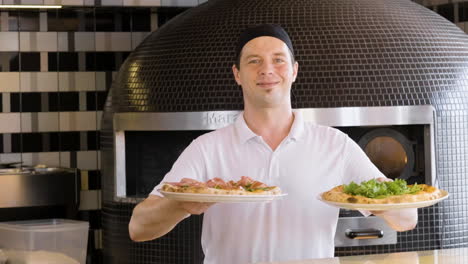 Glücklicher-Koch,-Der-Pizzas-Zeigt-Und-In-Die-Kamera-Im-Restaurant-Lächelt