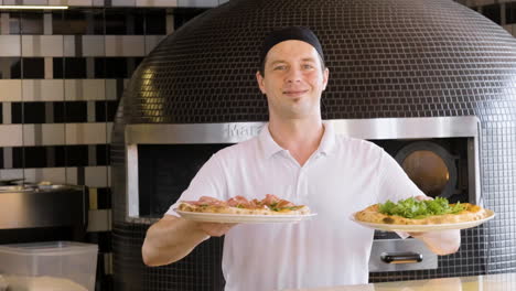 chef feliz mostrando pizzas y sonriendo a la cámara en el restaurante