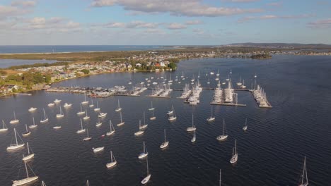 overhead drone of moored sailboats floating in rows across reflective water at sunset, textured backdrop