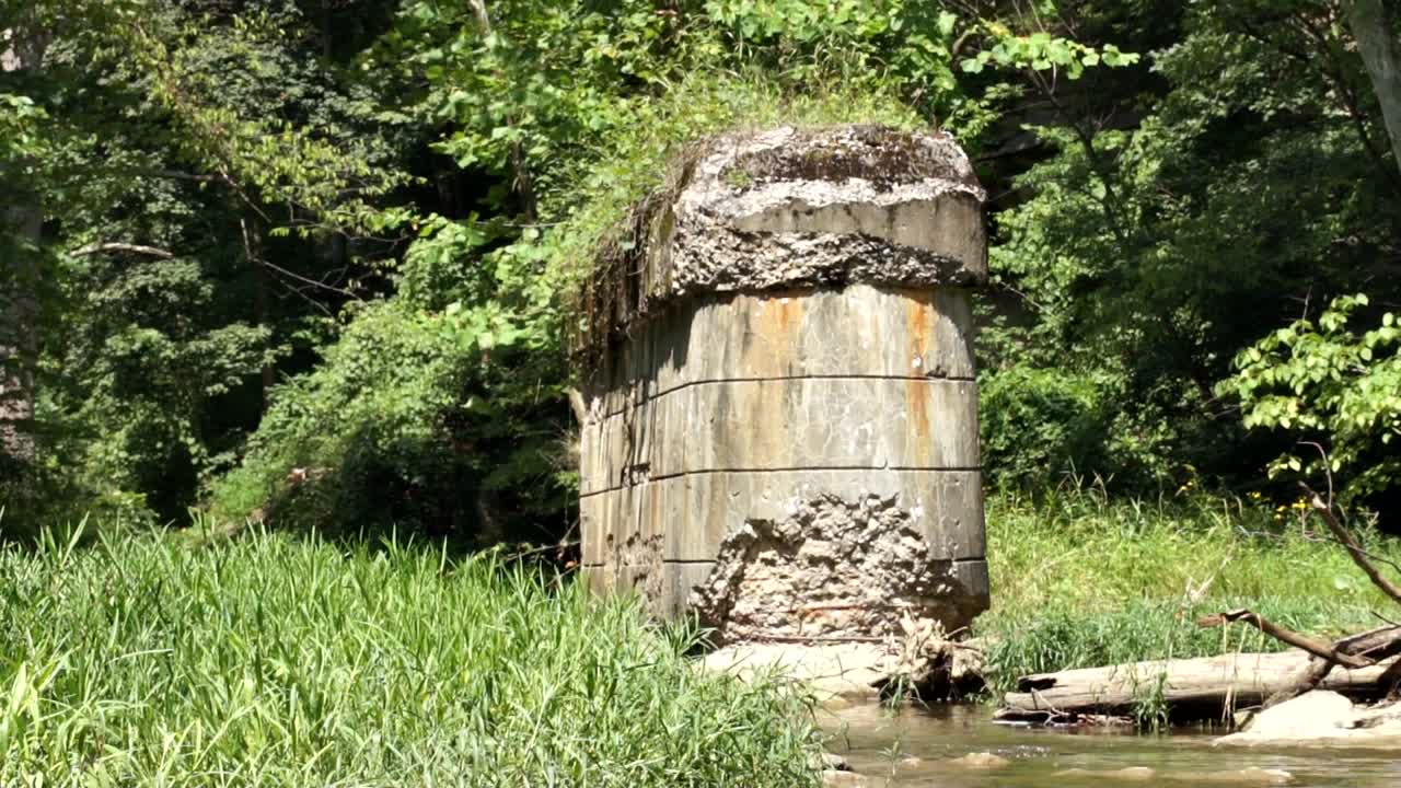 tiro inclinado hacia arriba del viejo pilón de puente derrumbado en medio del río del bosque