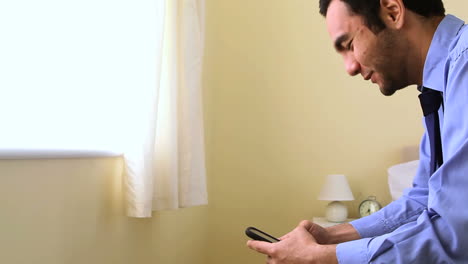 Portrait-of-a-businessman-texting-with-his-smartphone-in-bed