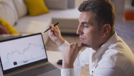 hombre comprobando las operaciones en el mercado de valores desde su computadora en casa.