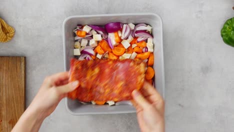 mujer de la cosecha poniendo costillas de cerdo en las verduras