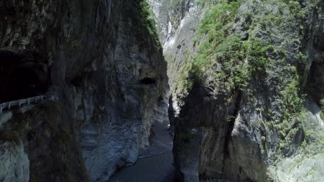 view from inside a canyon, with high almost vertical walls and some small caves on one side at taiwan, hualien.