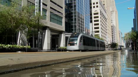 a rapid transit train moves quickly through downtown houston with fountains dancing 3