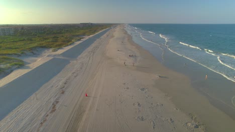 Drone-gracefully-gliding-above-the-coastline,-revealing-a-sun-drenched-beach-that-embodies-the-very-essence-of-Florida's-natural-splendor