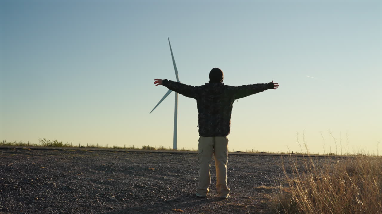 Man admiring wind turbines, connecting with nature and clean energy