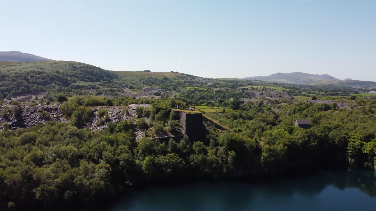 Cava di ardesia dismessa e ricoperta di vegetazione, Dorothea, in una fitta e lussureggiante foresta montana di Snowdonia, vista aerea in ascesa.