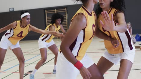 entrenamiento de un equipo de baloncesto femenino diverso con un entrenador masculino en una cancha cubierta, en cámara lenta