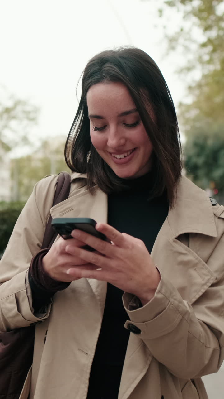 Giovane donna felice che sorride e usa lo smartphone all'aperto.