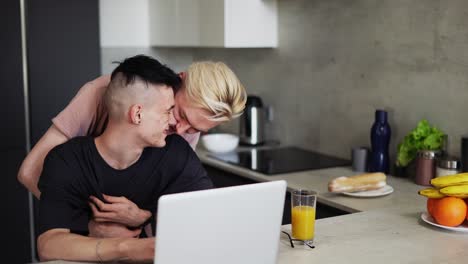 Guy-working-on-laptop-and-partner-holds-and-kiss-the-other