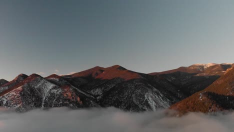 Luftschwenk-Mit-Goldenen-Sonnenaufgangsberggipfeln-über-Dem-Nebligen-Tal-Unten