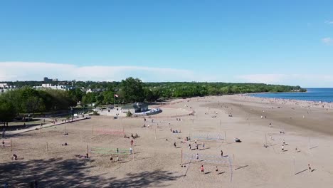 aerial shot flying over toronto beach on lake ontario with people playing volleyball