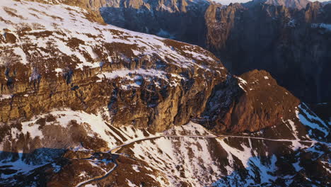 descending drone shot of a snow covered mountain road and ridge at mangart mountain in slovenia