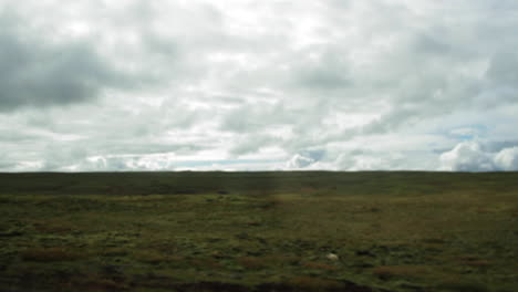 Car-Driving-Past-Open-Landscape-in-Iceland