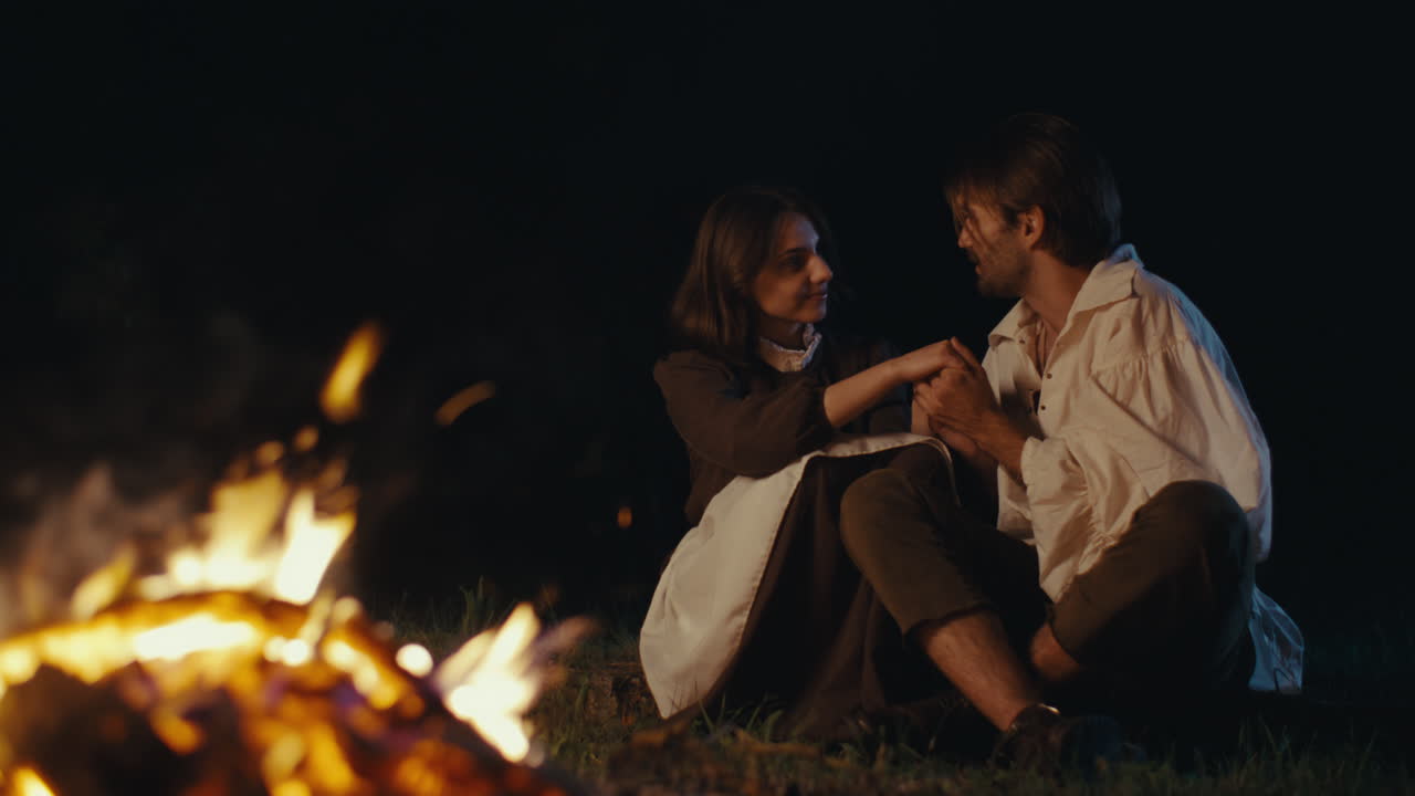 A couple sharing a romantic moment by a campfire at night