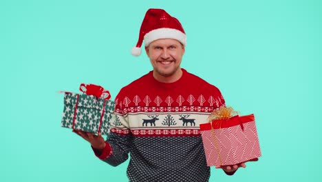 Cheerful-man-in-Santa-sweater-presenting-two-Christmas-gift-boxes,-stretches-out-his-hands-to-camera