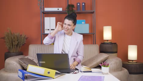 Home-office-worker-young-woman-scratches-her-ears-looking-at-camera.