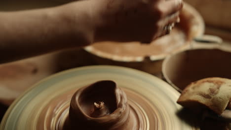 Unrecognized-lady-creating-clay-jar-in-pottery.-Closeup-woman-moistening-hands