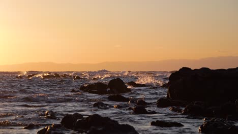 Paisaje-En-Cámara-Lenta-De-Olas-Rompiendo-Contra-Rocas-De-Silueta-Durante-La-Vibrante-Puesta-De-Sol