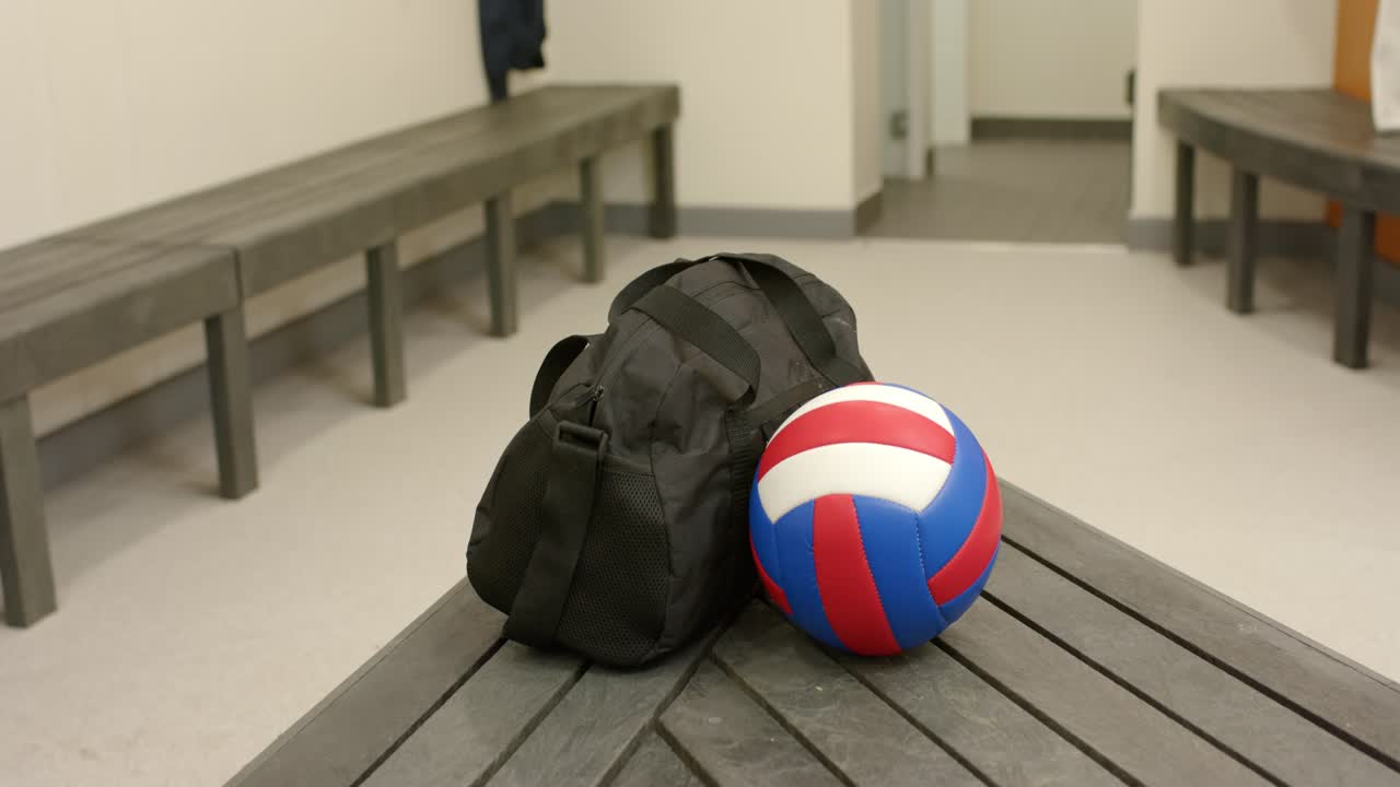 On recording start, black duffel bag and volleyball sitting on locker room bench awaiting practice
