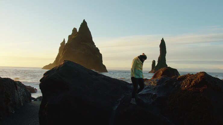 between rocks and the waves of the ocean at the Black Sand Beach in Iceland during the sunrise