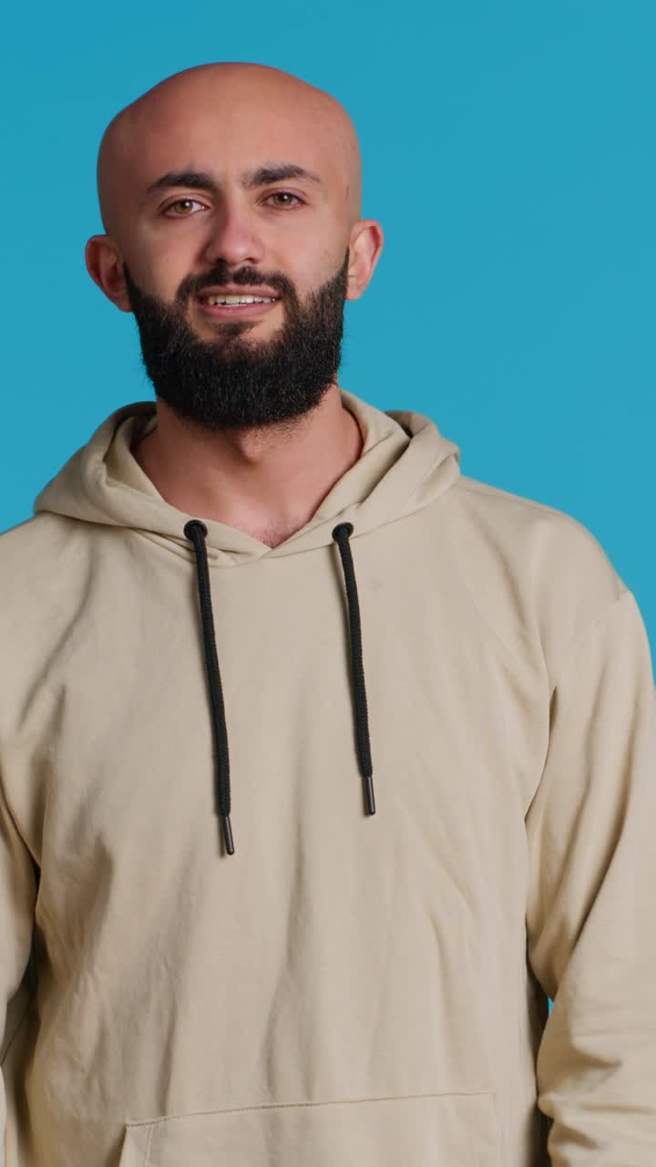 Vertical Video Arab male model doing no symbol on blue backdrop