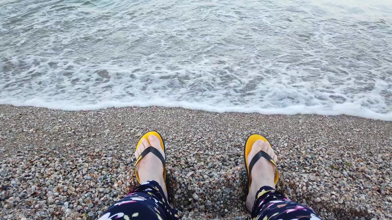 Deniz kenarında plaj terliğiyle bir kadın.