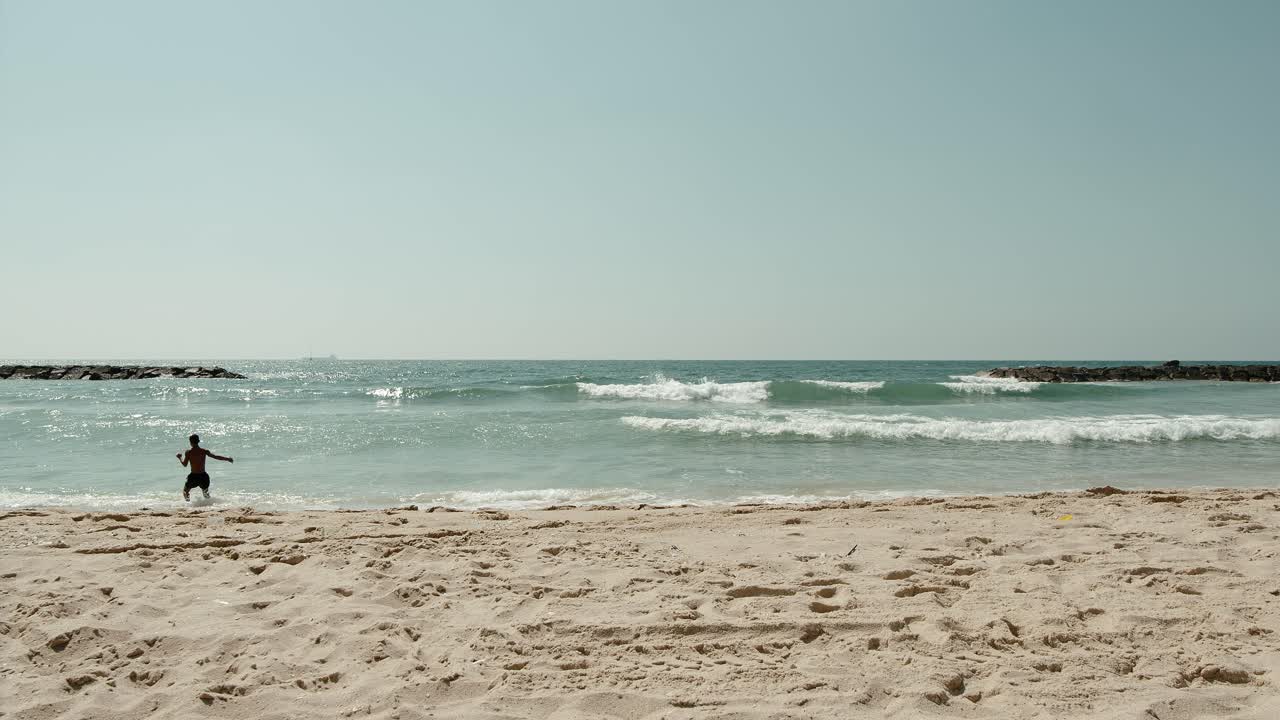 명랑한 소년은 푸른 해변으로 달려가 아늑한 물에 첨벙거린다