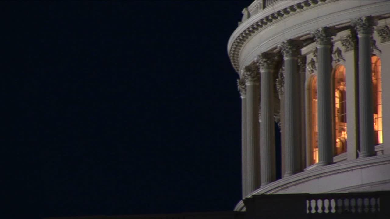 카메라는 밤에 조명이 켜진 국회 의사당 돔을 천천히 가로지릅니다.