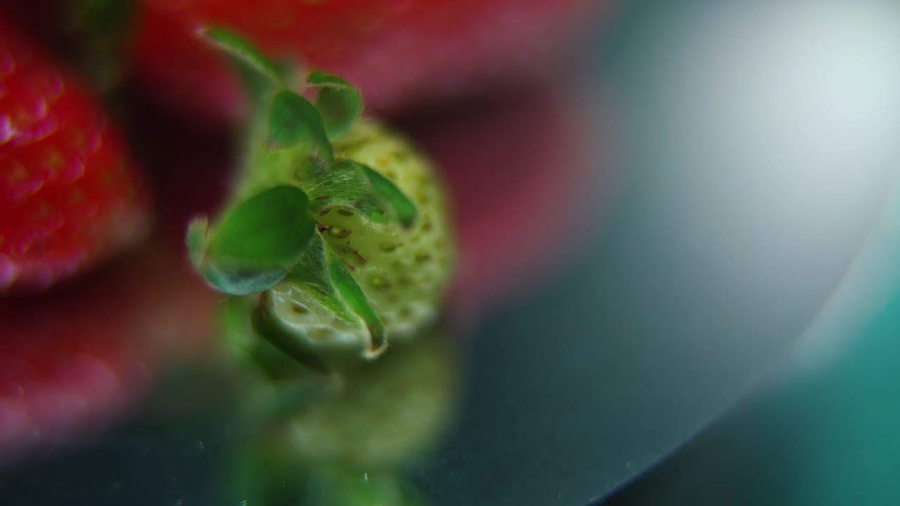 video macro detallado de una pila de fresas, pequeñas fresas verdes crudas, en un soporte giratorio, movimiento suave, cámara lenta 120 fps
