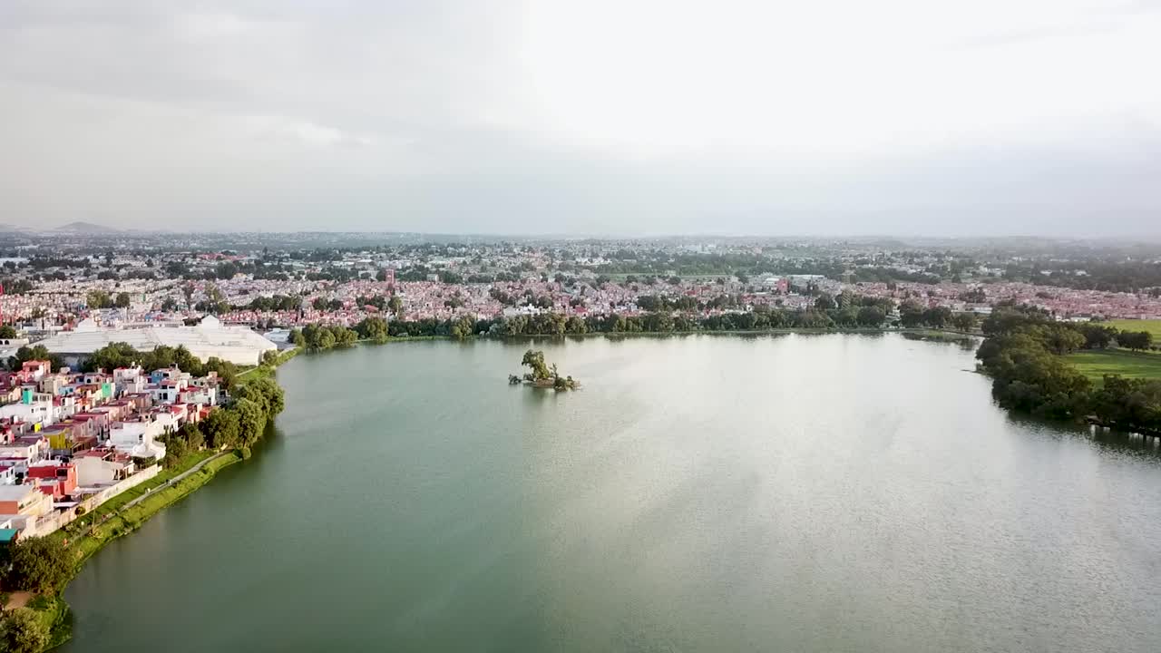 Panoramic aerial shot of Axotlán Lagoon in Cuautitlán Izcalli, State of Mexico, featuring an artificial islet in the middle, serving as a habitat for local wildlife