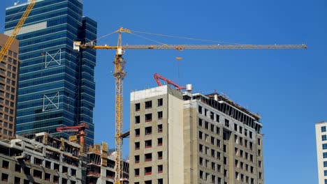 view on a construction crane and unfinished building in modern city in summer day