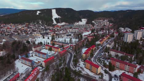 skikurs skisenter bjerke arvoll tonsengagen oslo norge norway aerial drone cold cloudy winter day gray skies city neighborhood buildings landscape arctic circle snowing backwards pan up motion