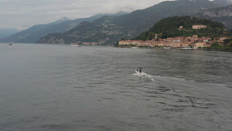 Drone-following-boat-on-a-vast-and-beautiful-lake-with-a-historical-city-in-the-background