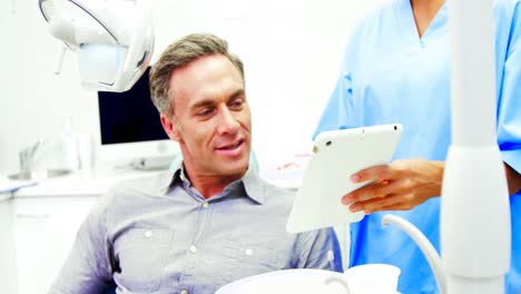 dentista mostrando una tableta digital a un paciente varón
