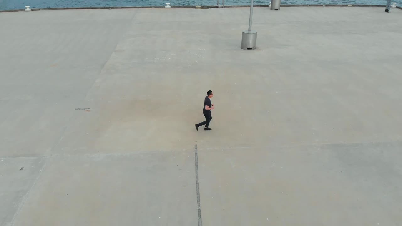 Drone Filming Asian Male Running On Princess Pier In Port Melbourne