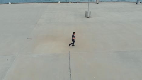 drone filming asian male running on princess pier in port melbourne