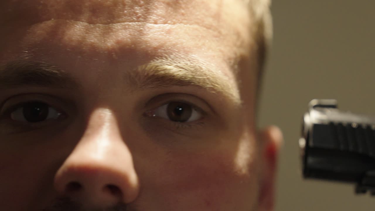 Someone is holding a gun to a man's temple. He has been kidnapped or is being robbed. close up