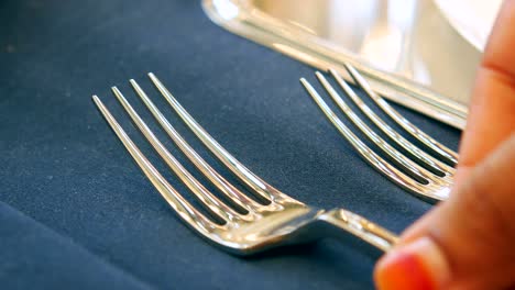 una mano con un tenedor de plata en un mantel de tela azul