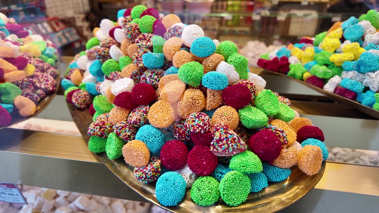Pile of Multicolored Candies with Sugar Sprinkles on a Golden Tray
