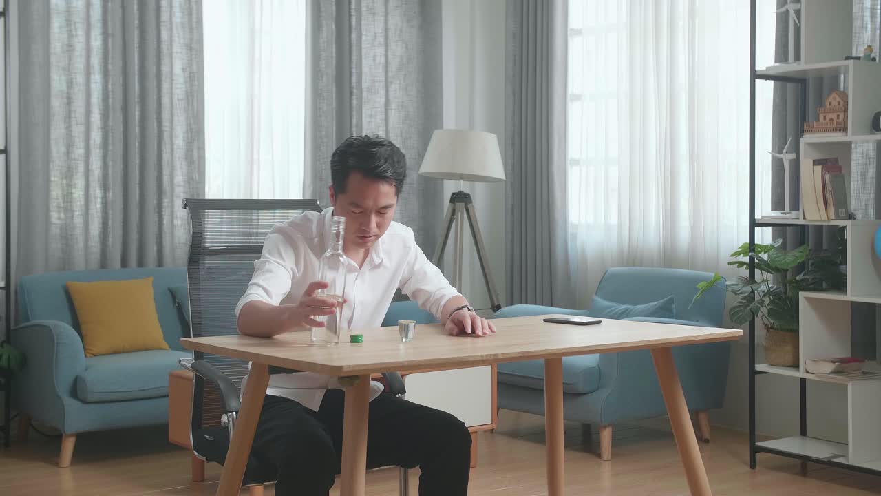 술에 취한 우울한 아시아인 남자가 집에서 테이블을 부러뜨리기 전에 보드카를 마시고