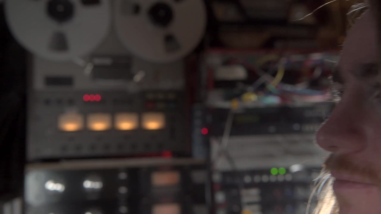 productor grabando música en un carrete a carrete grabadora de cinta antigua en el estudio de grabación