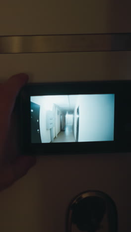 pov de una persona que utiliza un monitor de agujero de mirada digital para comprobar el pasillo fuera de su puerta para mejorar la seguridad del hogar