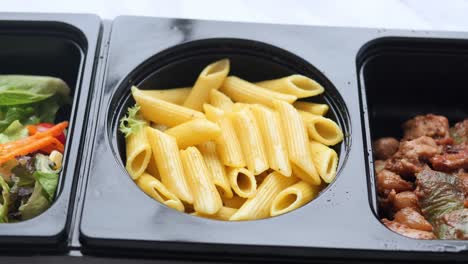 healthy meal prep with penne pasta, salad, and chicken